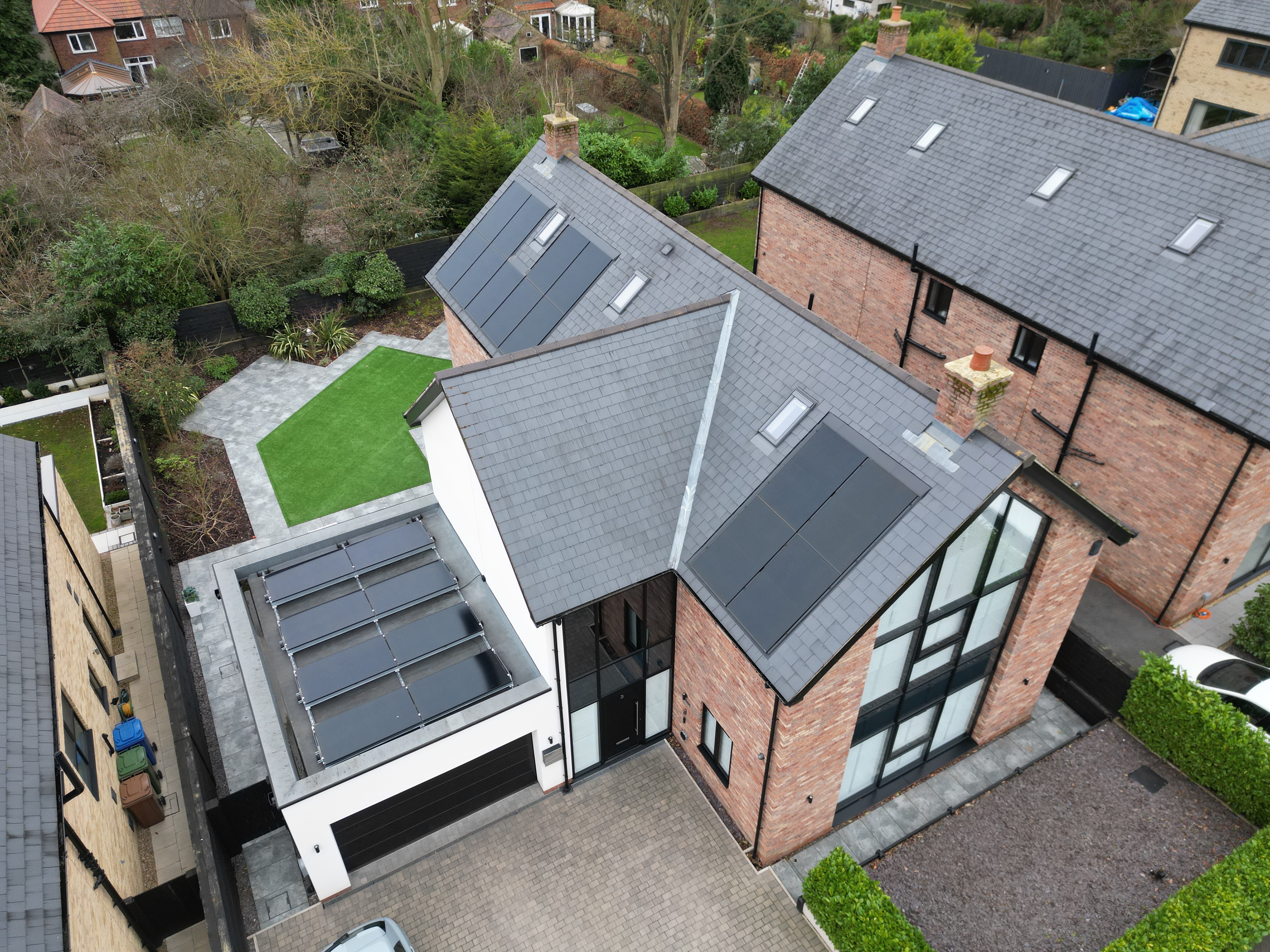Drone view of all-black in-roof solar panels on a slate roof and a flat-roofed garage at a home in Hessle