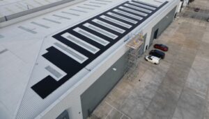 Aerial view of an 86 kWp all-black solar array on a profiled metal industrial roof with rooflights in Doncaster