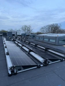 East-west solar rows on Esdec ballasted mounting on a flat campus roof at the University of Kent, beside rooflights and plant