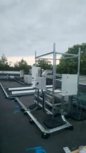 SolarEdge inverter and isolator on a galvanised steel frame on a University of Kent roof, fed by DC cable tray on ballast feet